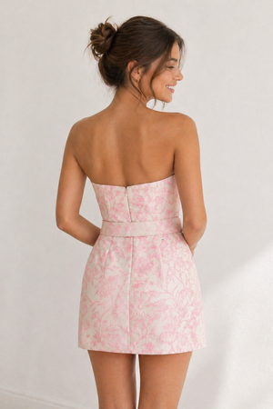 Woman wearing a pink floral strapless dress against a white background