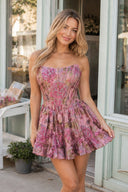 Woman wearing a floral dress standing on a sidewalk with storefronts in the background